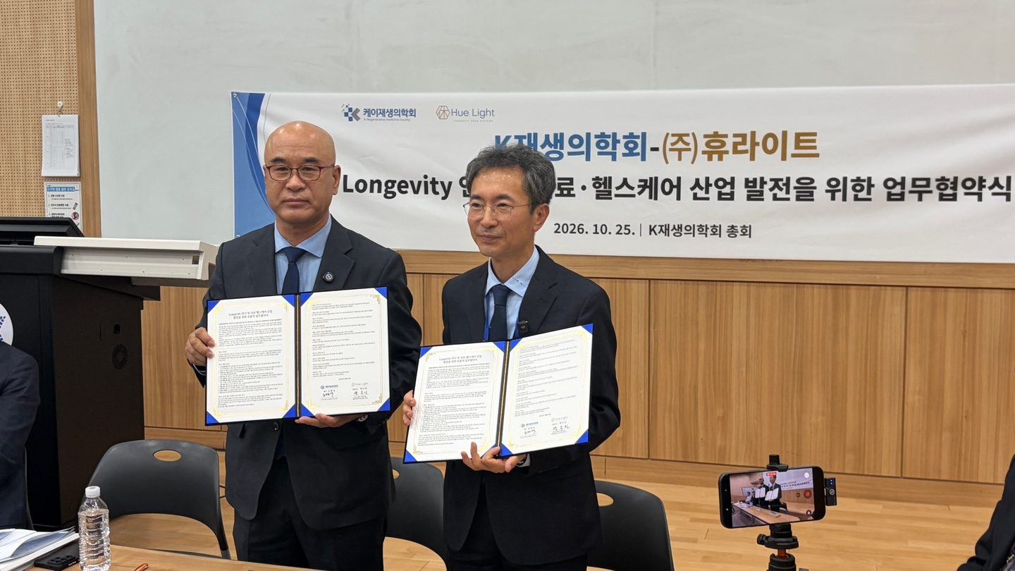 The heads of K-Regenerative Medicine Society and Hue Light holding the signed agreement in front of the ceremony banner