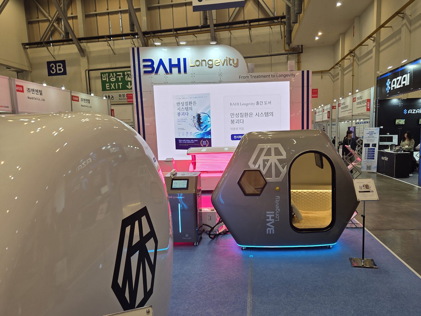 KIMES 부산 2026 벡스코 B400 부스. 왼쪽 앞에 흰 BAHI O₂ Duo, 가운데 은색 육각형 BAHI O₂ Hexagon, 뒤로 BAHI Longevity 벽